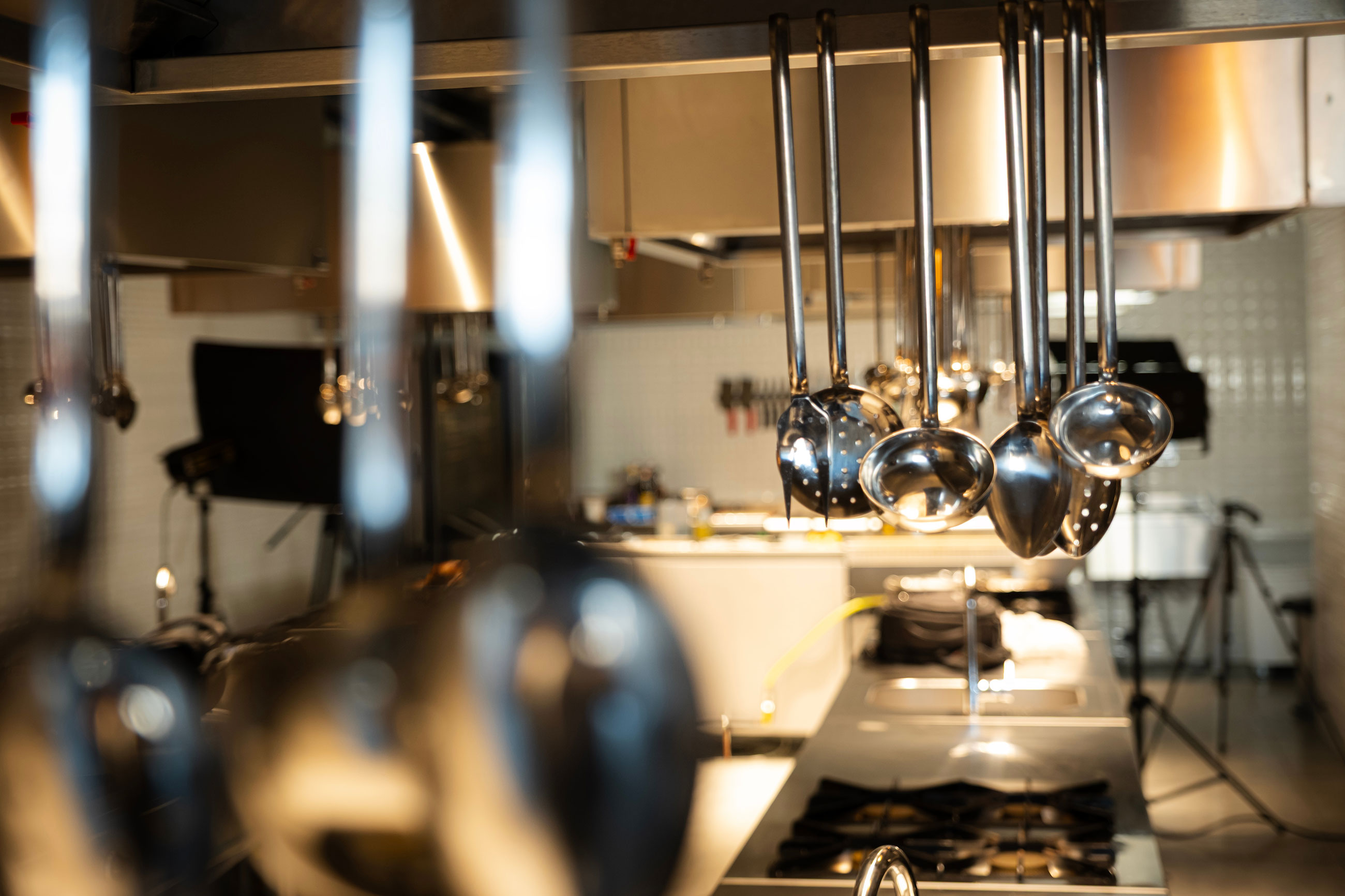 Commercial kitchen prep line with hanging ladles and stainless equipment